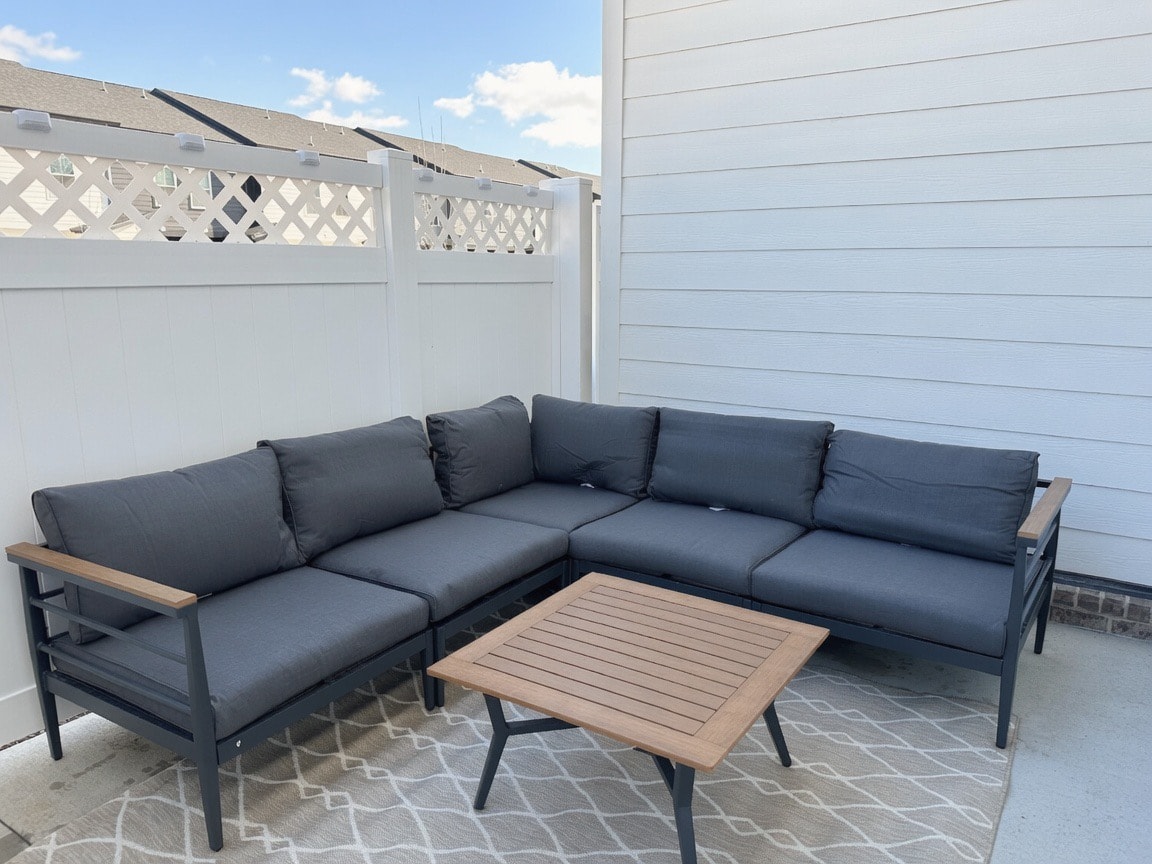 Staged outdoor patio with dark sectional and wood coffee table